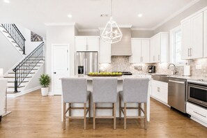 A modern kitchen with a central island, stainless steel appliances, and a staircase on the left. - The Retreat, 3BR Wlk-SQ+grill by Velvet Ditch Villas (Oxford)