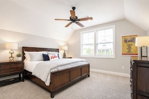 A bedroom with a wooden bed, two bedside tables with lamps, a ceiling fan, a large window, and a poster on the wall. - The Retreat, 3BR Wlk-SQ+grill by Velvet Ditch Villas (Oxford)