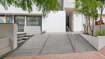 Ein Innenhof mit einer Treppe, die zu einer Tür führt, umgeben von weißen Wänden und Blumentöpfen.