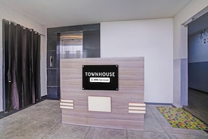 Ein Empfangsschalter mit einem Schild, das 'TOWNHOUSE' und 'OYO-Serviced' zeigt.