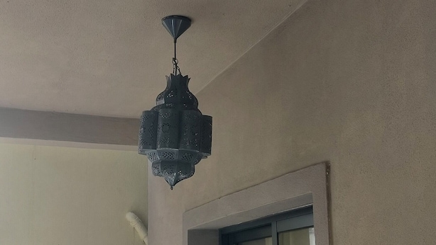 Een balkon met een witte reling, een hanglamp en een raam met uitzicht.