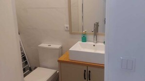 Een badkamer met toilet, wastafel, spiegel en kast.