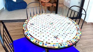 A dining area with a round table, blue chairs, and a colorful mosaic floor.