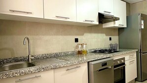 A modern kitchen with white cabinets, stainless steel appliances, and a granite countertop.