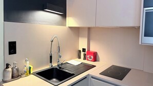 Een moderne keuken met een zwarte spoelbak, een roestvrijstalen kraan en een rode apparate op het aanrecht.
