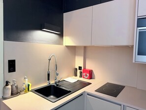 Eine moderne Küche mit einem schwarzen Spülbecken, einem Edelstahlarmaturen und einem roten Gerät auf der Arbeitsplatte.