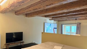 Een slaapkamer met een groot bed, een flatscreen televisie en een raam met gordijnen.