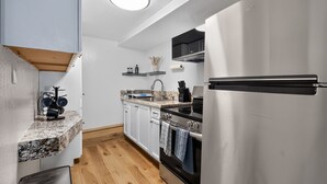 Eine moderne Küche mit weißen Schränken, einem Edelstahlkühlschrank, einem Einbauofen und einer Arbeitsplatte aus Granit.