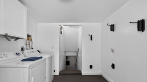A laundry area with a washing machine, dryer, and a hallway leading to a bedroom.
