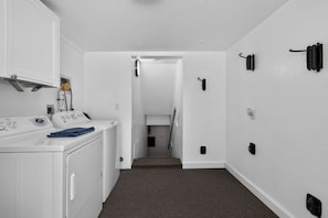 A laundry area with a washing machine, dryer, and a hallway leading to a bedroom.