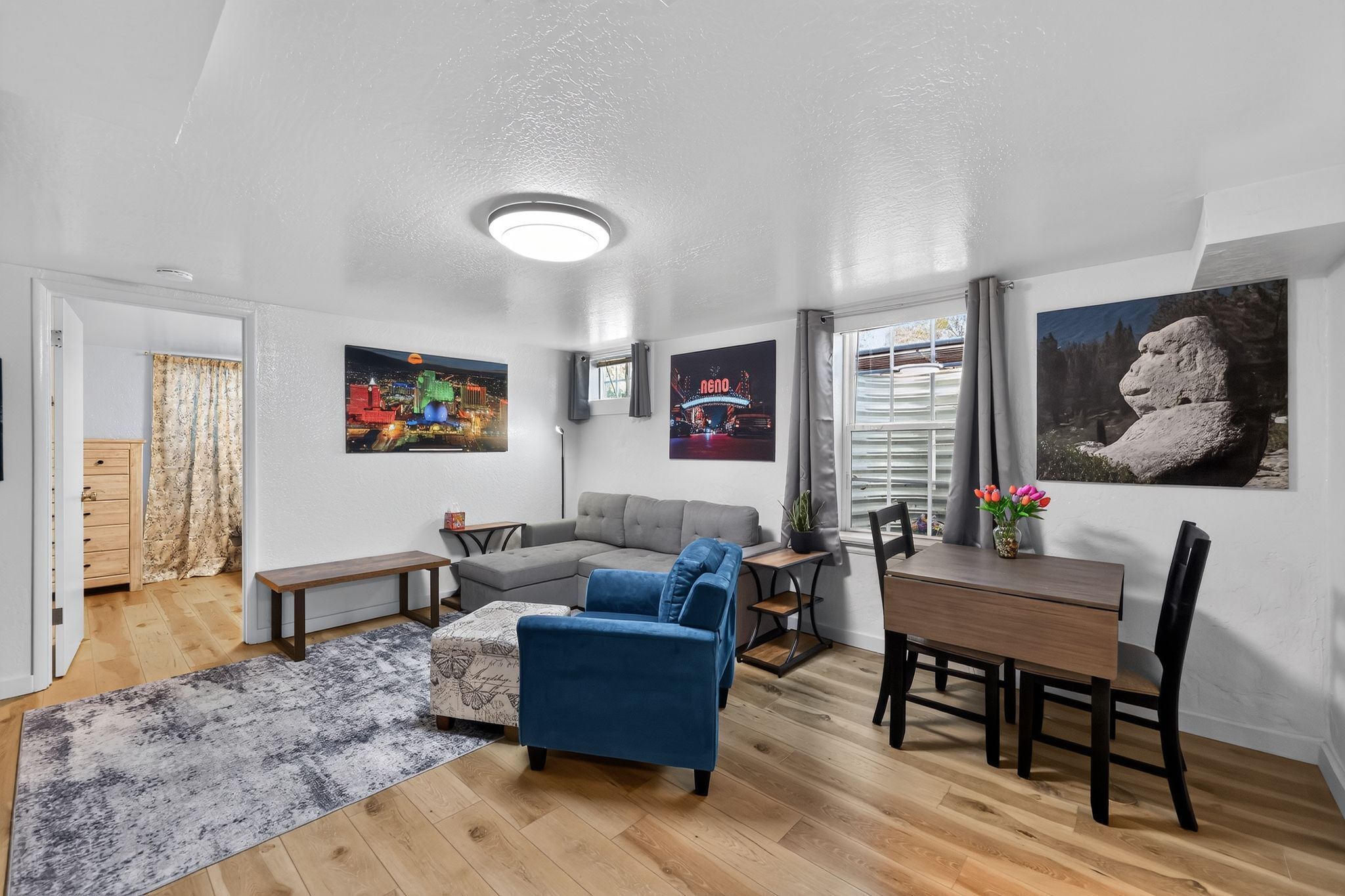 A modern living room with a sectional sofa, a dining table, and a large window.