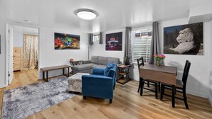 Ein modernes Wohnzimmer mit einem Ecksofa, einem Esstisch und einem großen Fenster.