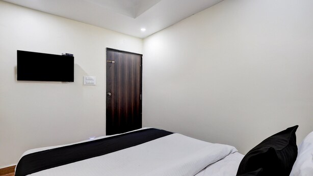 Een slaapkamer met een bed, een flatscreen-tv aan de muur, een deur en een plafondlamp.