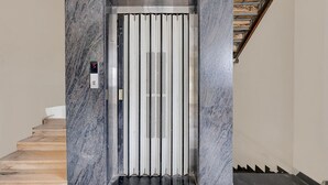 Een lift met een digitaal scherm, een metalen interieur en een marmeren wand.