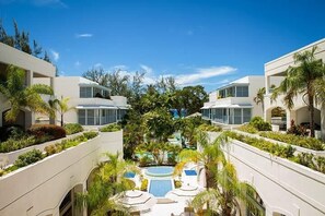 Ein Hotel mit einem zentral gelegenen Pool, umgeben von üppiger Vegetation und mehreren Balkonen.