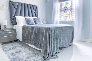 Ein modernes Schlafzimmer mit einem Bett, Nachttischen, einem Teppich und einem Fenster mit Vorhängen.