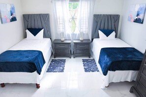 Ein Doppelzimmer mit modernem Design, zwei Nachttische, ein Fenster mit Vorhängen und Kunstwerken an den Wänden.