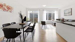A modern kitchen with a dining area, a large window, and a balcony.