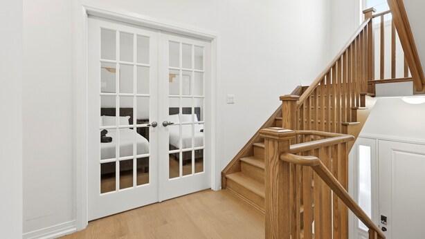 A staircase with wooden railings leading to a room with a bed and a white door.