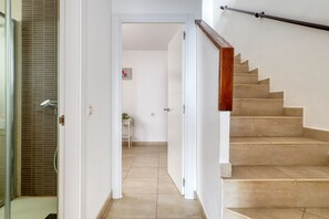Eine Treppe führt zu einer oberen Etage, eine Tür mit Fensterglas und ein Fliesenboden.