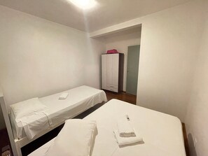 Ein Zimmer mit zwei Einzelbetten, einem Kleiderschrank und einer Tür zu einem anderen Raum.