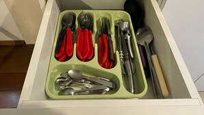 A drawer with compartments containing various kitchen utensils.