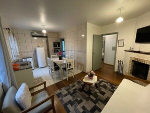 A compact living space with a dining area, kitchen, and a fireplace. - Residencial Tristão de Oliveira (Gramado)