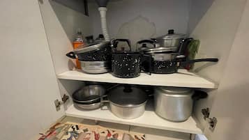 A kitchen with multiple shelves holding various pots and pans.