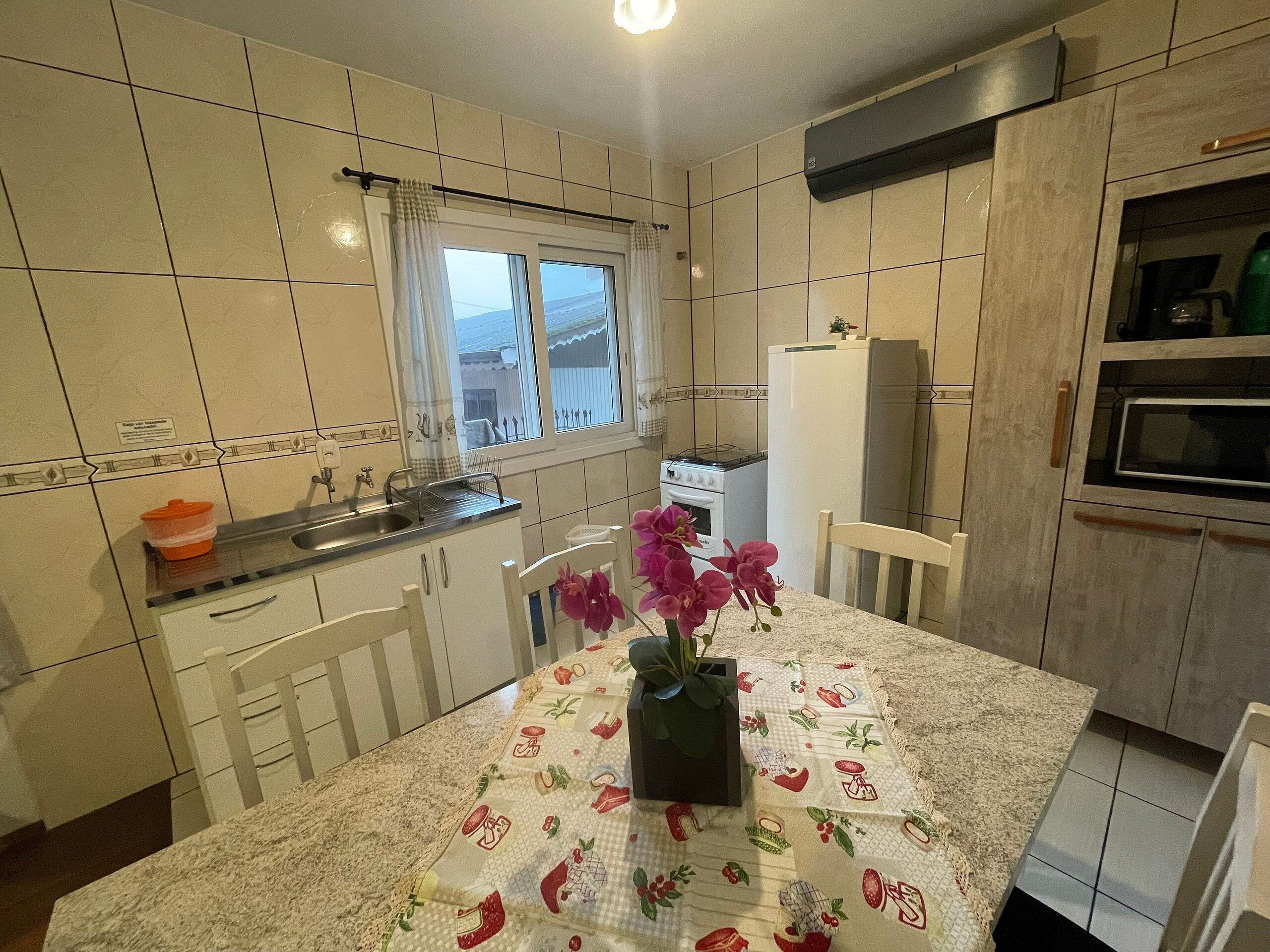 A kitchen with a dining table, chairs, a refrigerator, a stove, and a window.