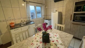 A kitchen with a dining table, chairs, a refrigerator, a stove, and a window.