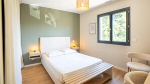 A bedroom with a bed, bedside tables, a chair, a window, and a hanging light fixture. - Beautiful Montpellier Villa With Pool (Montpellier)