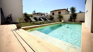A rectangular swimming pool with a wooden deck, surrounded by lounge chairs and potted plants. - Beautiful Montpellier Villa With Pool (Montpellier)