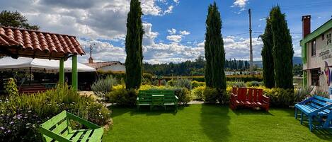 A well-maintained lawn with a green bench, a red bench, and a blue bench.