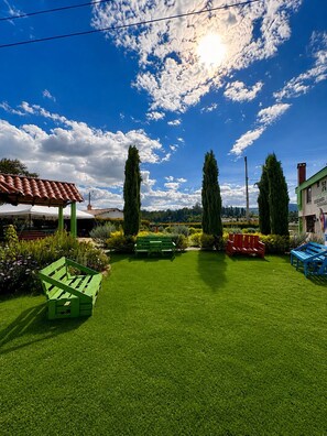 A well-maintained lawn with a green bench, a red bench, and a blue bench. - Casa Hotel Descanso Real (Paipa)