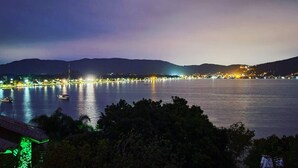 Une ville côtière de nuit, avec une mer calme, des bateaux et une silhouette urbaine lointaine.