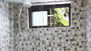 Une salle de bain comprenant des toilettes, un espace douche et une fenêtre.