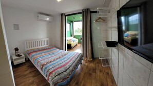 Une chambre à coucher avec un lit, une table de chevet, une lampe suspendue, une fenêtre et une vue sur une autre pièce.