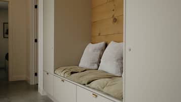 Un dormitorio con un banco empotrado, un revestimiento de pared de madera y un armario blanco.