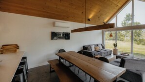 Et moderne interiør med træloft, et stort vindue, et spisebord og en sofa.