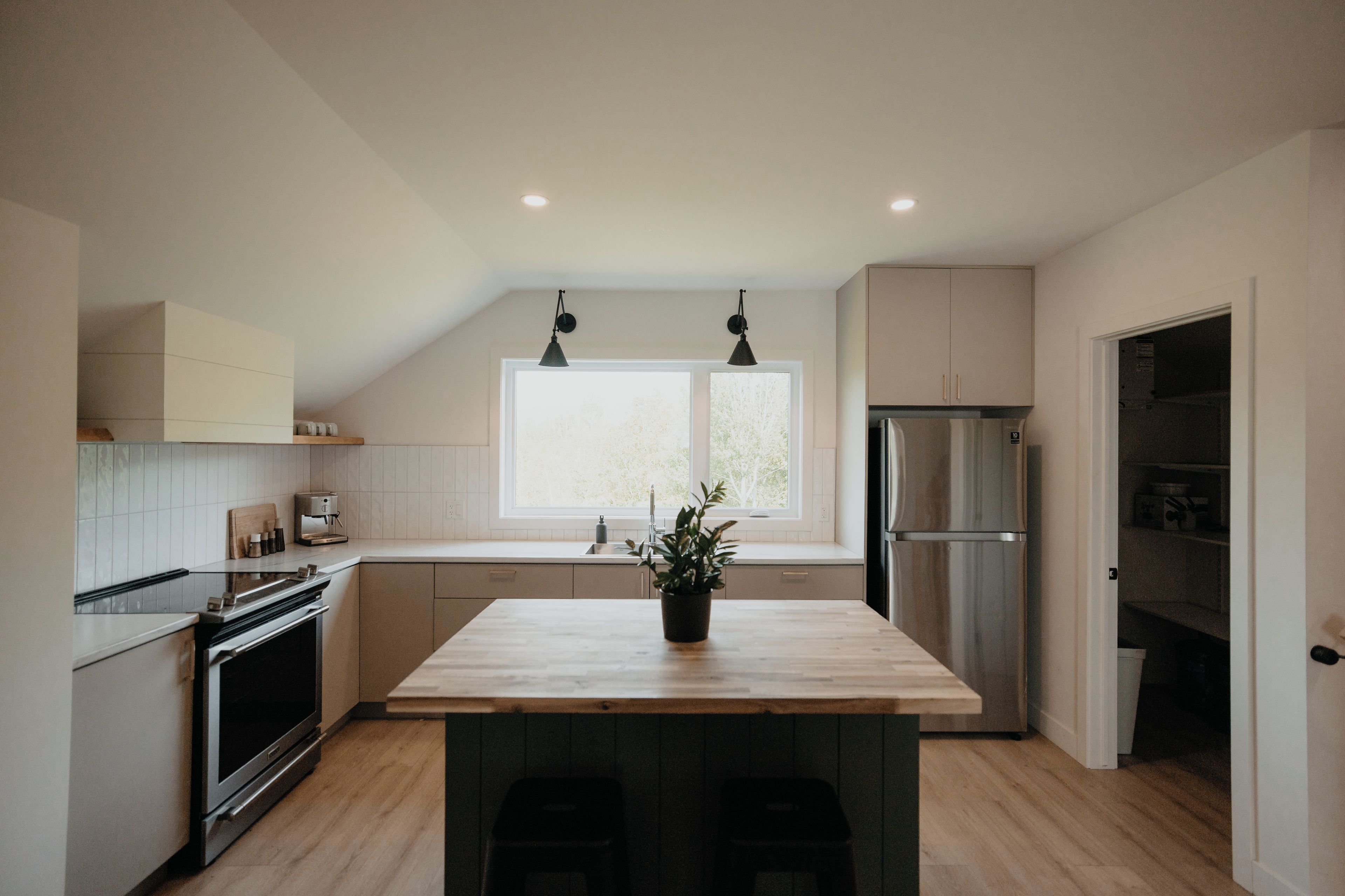 A modern kitchen with a wooden island, stainless steel appliances, and a window providing natural light.