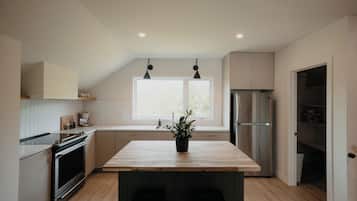 A modern kitchen with a wooden island, stainless steel appliances, and a window providing natural light.
