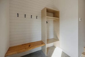 Una habitación con un banco de madera, un banco empotrado y un perchero de pared.