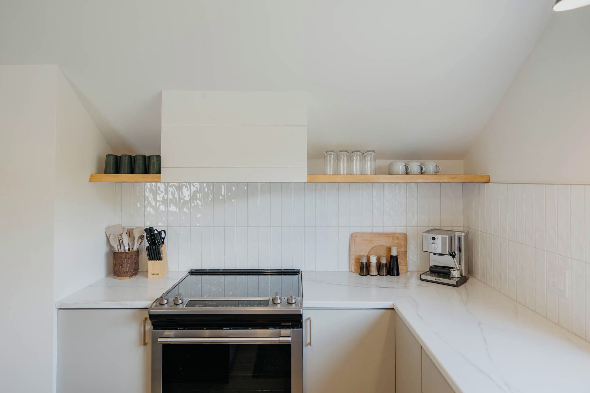 Una cocina compacta con horno empotrado, cafetera y bloque para cuchillos.