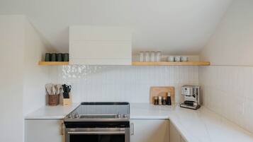 Una cocina compacta con horno empotrado, cafetera y bloque para cuchillos.