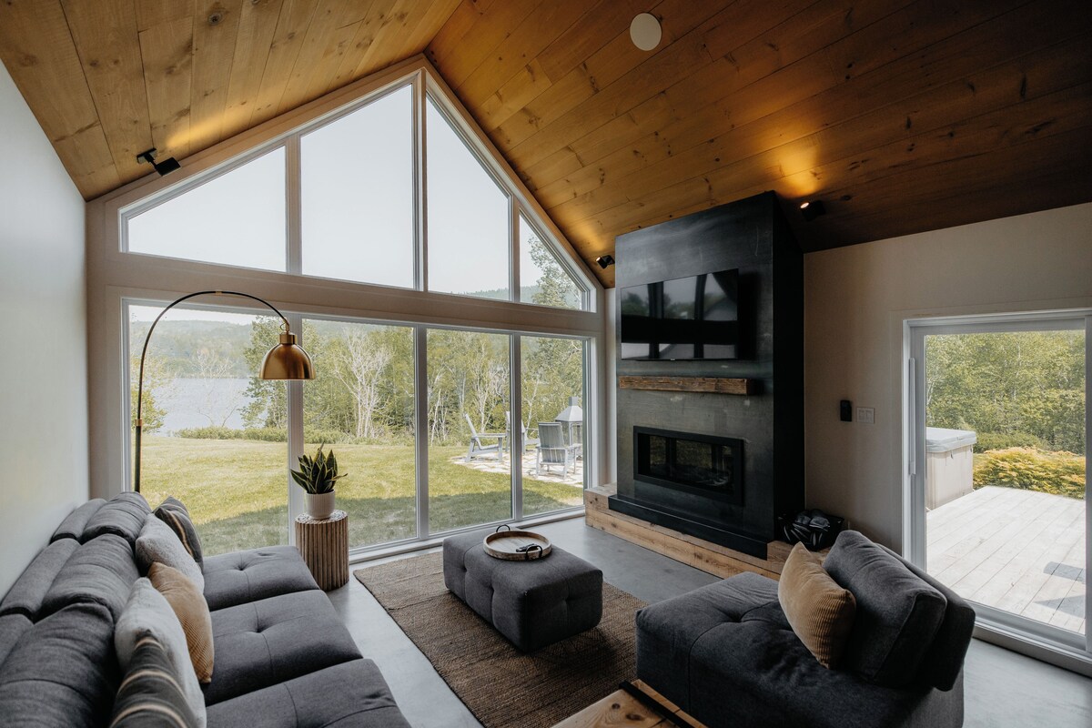 Una sala de estar moderna con chimenea, ventanas amplias y un rincón de descanso acogedor.