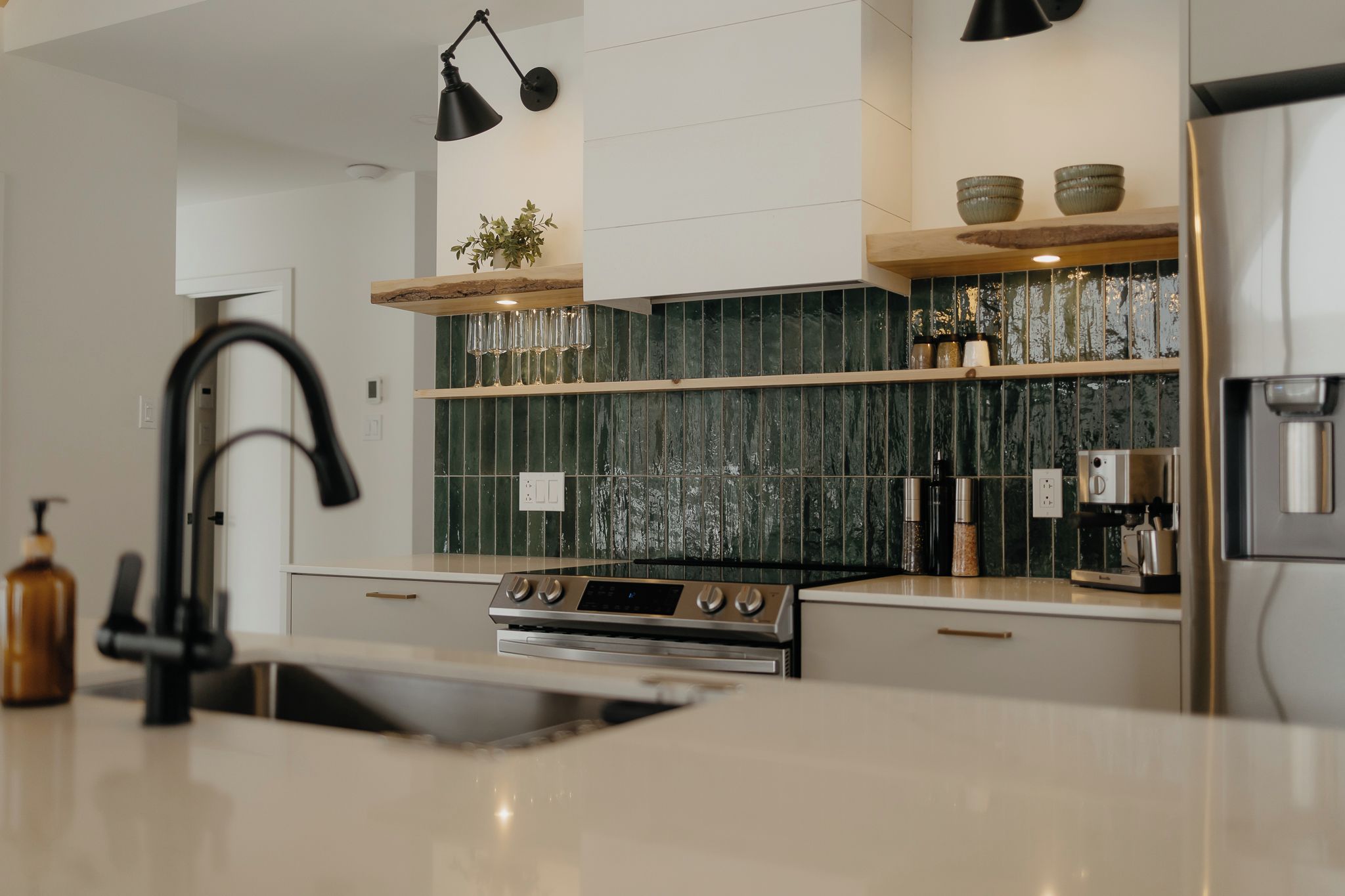 A modern kitchen with a stainless steel stove, black faucets, and a marble countertop.
