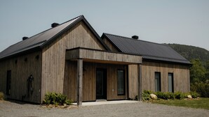 En moderne træbygning med skråt tag, store vinduer og en grusvej.