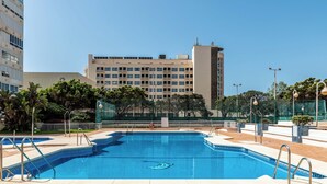Ein Pool mit Stufen, umgeben von einem Zaun, mit einem Gebäude im Hintergrund.
