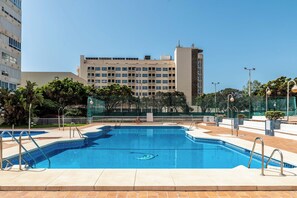 Ein Pool mit Stufen, umgeben von einem Zaun, mit einem Gebäude im Hintergrund.