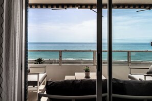Un balcon donnant sur la plage, une plante en pot et une table.